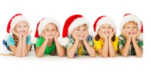 Group of happy Christmas kids in Santa hat lying down. White bac